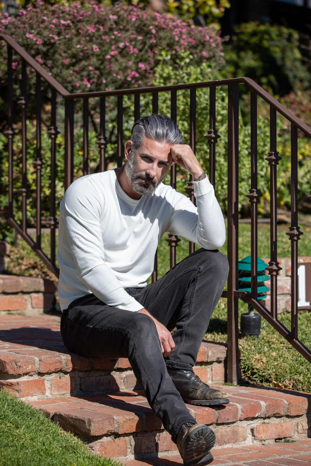 Man sitting on steps outdoors with a garden in the background