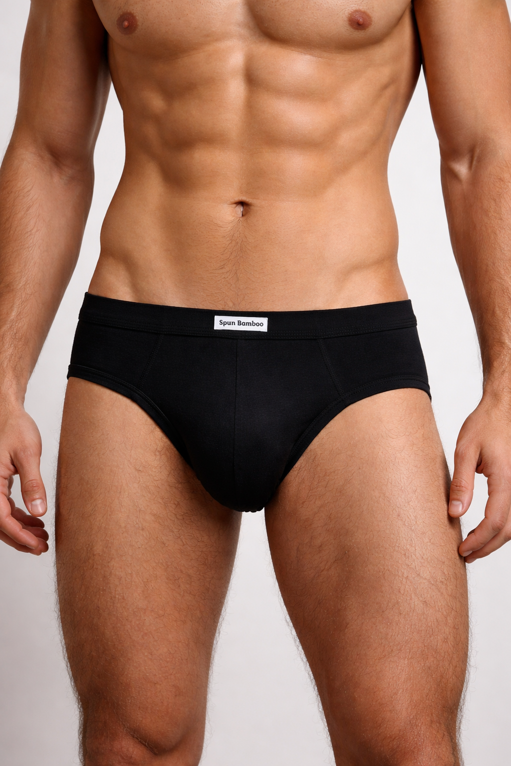 Man wearing black underwear with a visible brand logo on a plain background