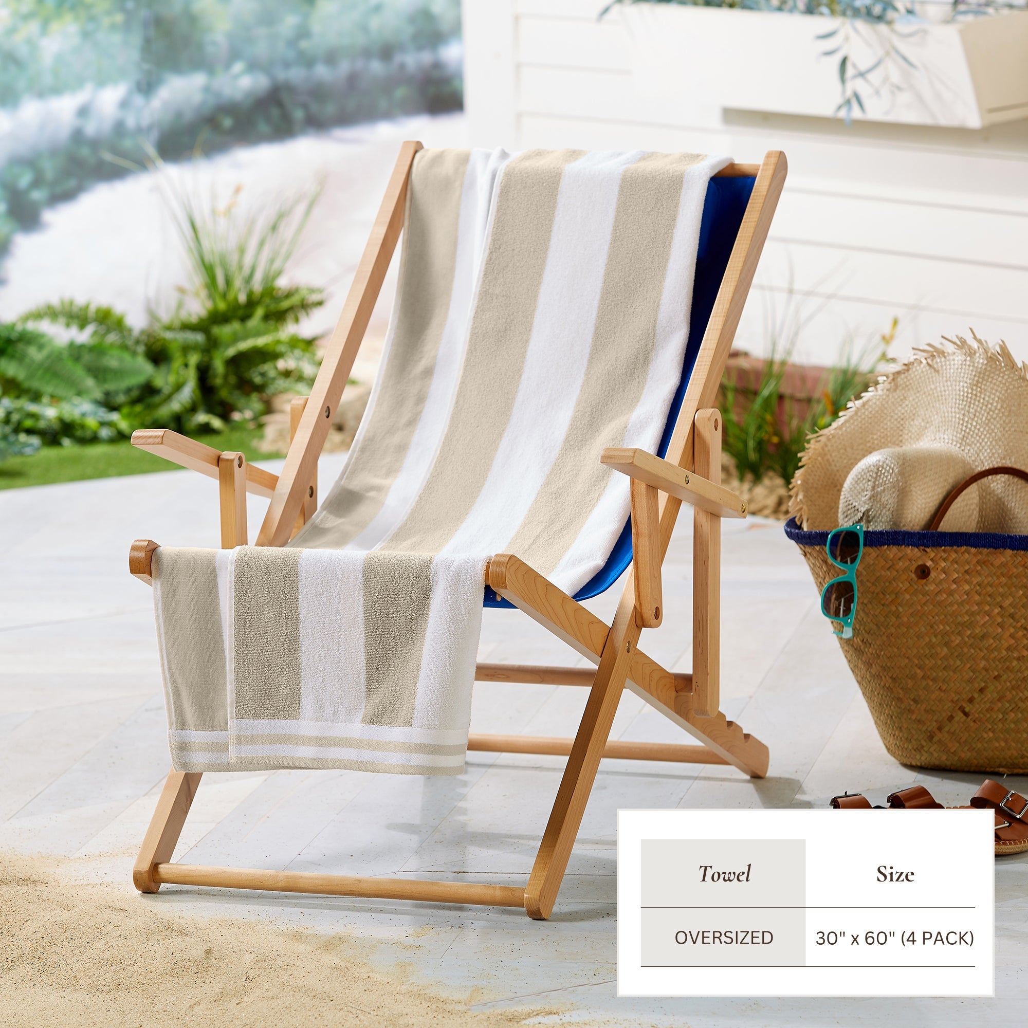 Beige and white striped towel draped over a wooden deck chair with a wicker basket and sunglasses on a patio.