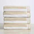 Stack of beige and white striped towels on a light wooden surface with a white background