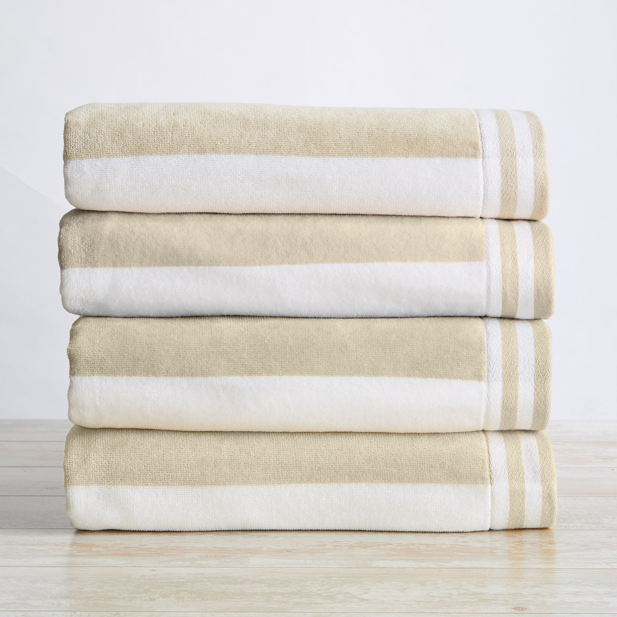 Stack of beige and white striped towels on a light wooden surface with a white background