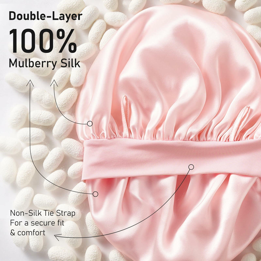 Pink satin bonnet with text highlighting double-layer 100% mulberry silk and non-silk tie strap on a white background.